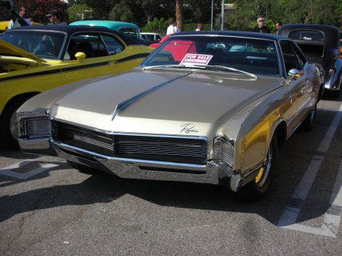 1998 Ford Crown Victoria - Photograph of a gold late-1960s Buick Riviera with a For Sale windshield sign, not a technical document.