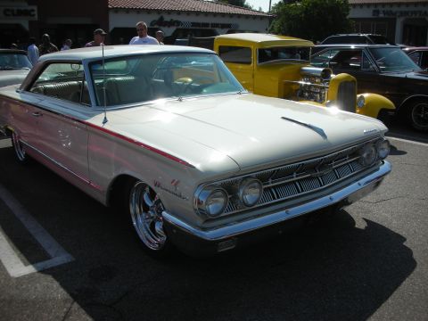 1998 Ford Crown Victoria - Photograph of a white early-1960s Mercury hardtop parked at a car show, not a technical document.