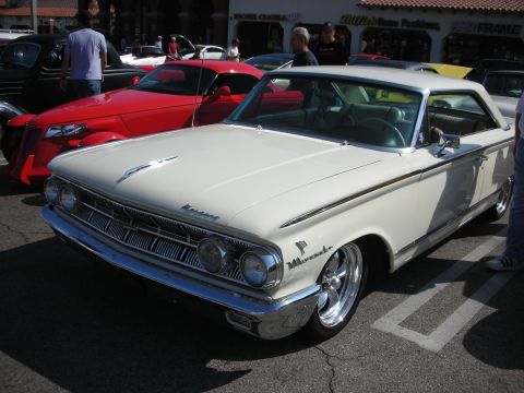 1998 Ford Crown Victoria - Photograph of a white 1960s Mercury hardtop at a street car show, not a technical document.
