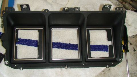 1979 Ford Bronco - This is a dashboard instrument cluster housing. It has three openings with white material and a blue stripe.