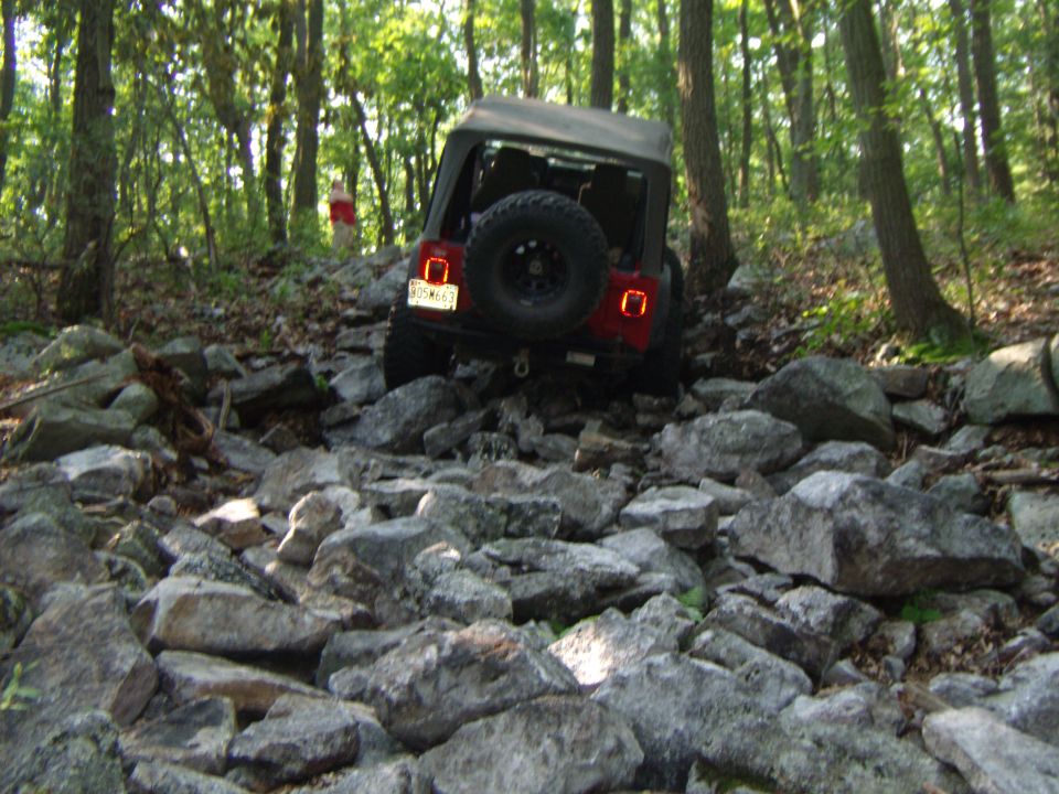 2003 Jeep Wrangler navigating a rocky trail in a forest