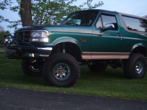 1996 Ford Bronco - A lifted 1996 Ford Bronco in green with tan trim is shown from a 3/4 front angle.