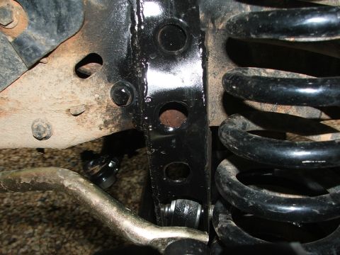 1996 Ford Bronco - Close-up view of vehicle suspension components including a bracket and coil spring.