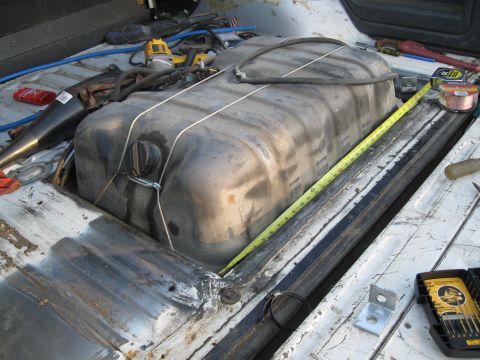 1991 Ford Bronco - A large fuel tank is secured with straps in a vehicle's cargo area, ready for installation.