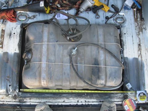 1991 Ford Bronco - A fuel tank is shown with attached hoses and securing straps, with a measuring tape visible underneath.