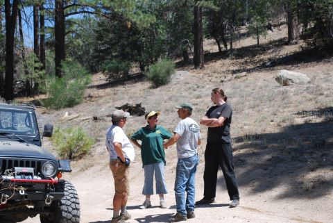 1996 Ford Bronco - A group of people stand near a 1996 Ford Bronco on a dirt road surrounded by trees.