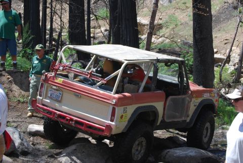 1996 Ford Bronco - This modified off-road vehicle navigates a rocky trail, a prominent roll cage and a two-tone red and white paint scheme.