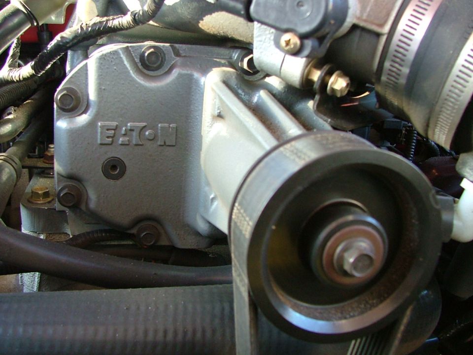 Eaton supercharger housing in an engine bay with a tool on the pulley