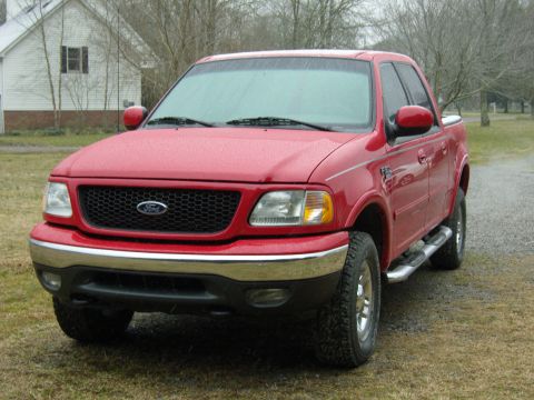 2007 Ford Mustang - Photograph of a red Ford F-150 crew-cab pickup, front three-quarter view on grass.
