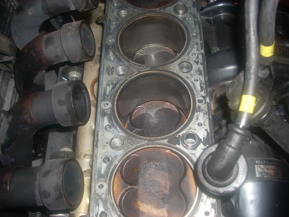 Engine cylinder block with pistons and exhaust manifolds
