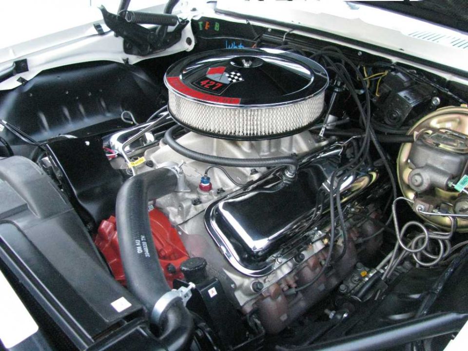 Close-up of a V8 engine bay with chrome air cleaner and black radiator hose.