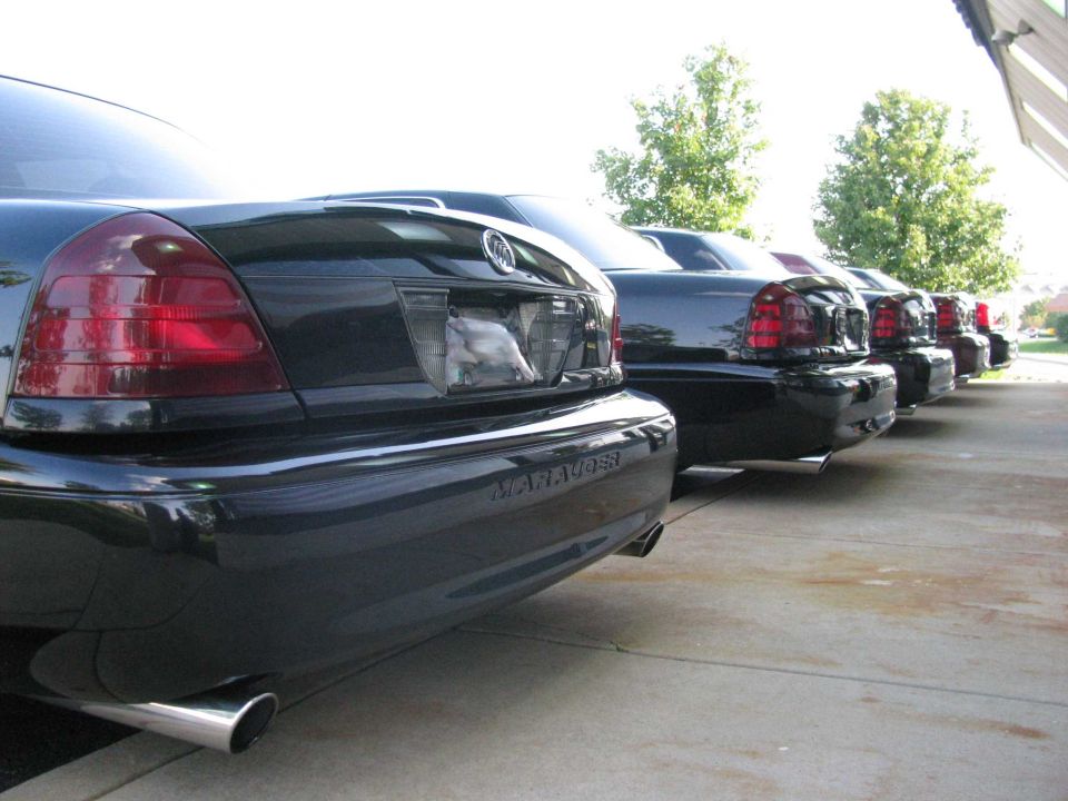 Line of black Mercury Marauder sedans, rear view, showing chrome exhaust pipes.