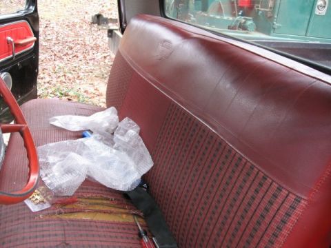 1966 Ford F-100 - Interior shot of a freshly reupholstered red bench seat in a vintage Ford pickup, combining smooth red vinyl bolsters with a red houndstoot…