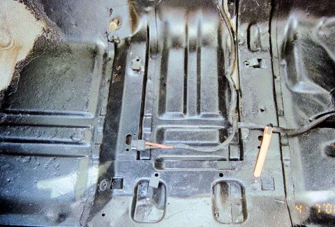 1976 Ford Ranchero - The bare metal floor pan of a vehicle, showing structural supports and wiring harnesses.