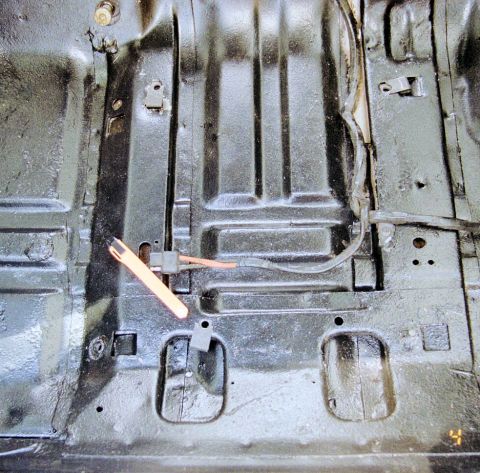1976 Ford Ranchero - Close-up of a vehicle's interior floor pan, showing black paint and exposed wiring.