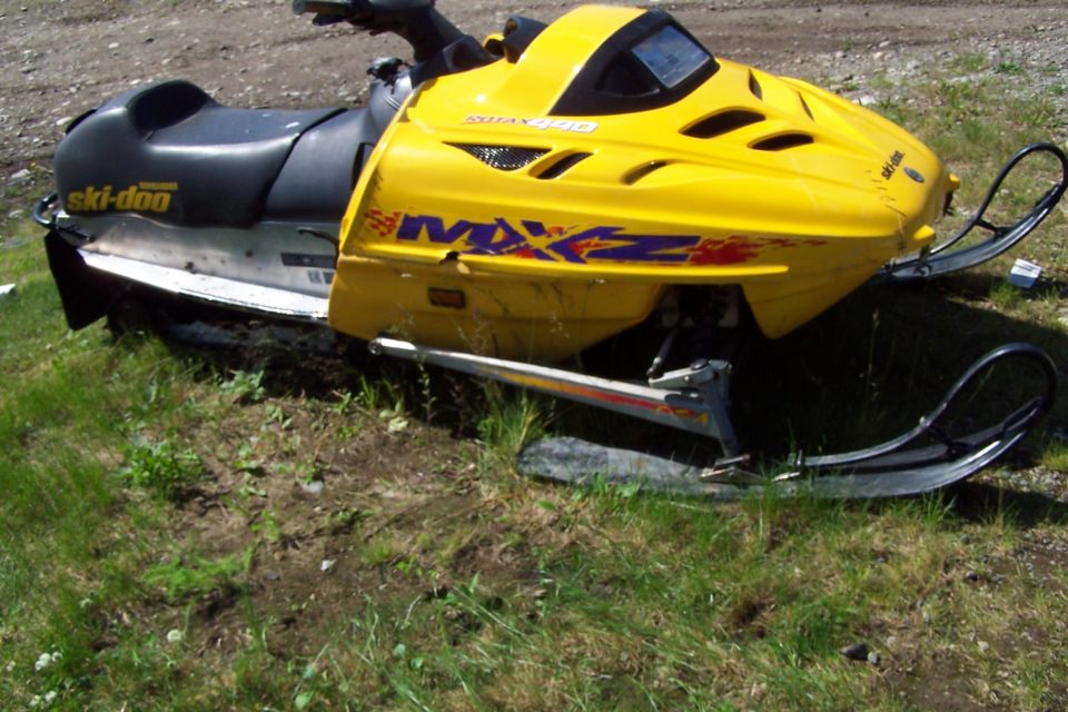 Yellow Ski-Doo snowmobile with black seat and silver trim parked on grass.