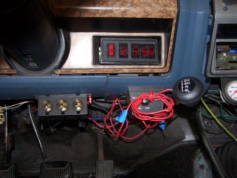 1986 Ford Bronco - Interior view of a vintage Ford Bronco dashboard showing a row of four red-lit toggle switches, a gear shifter with 2H, 4H, N, and 4L marki…