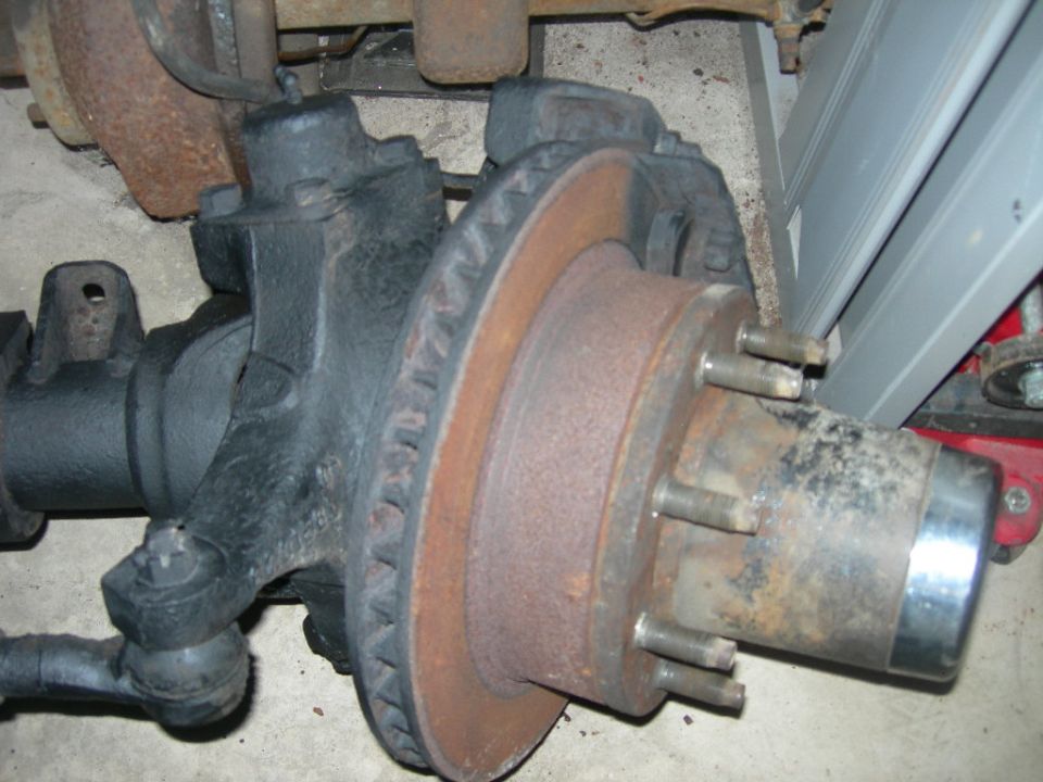 Rusty brake rotor and hub assembly on a black axle housing.