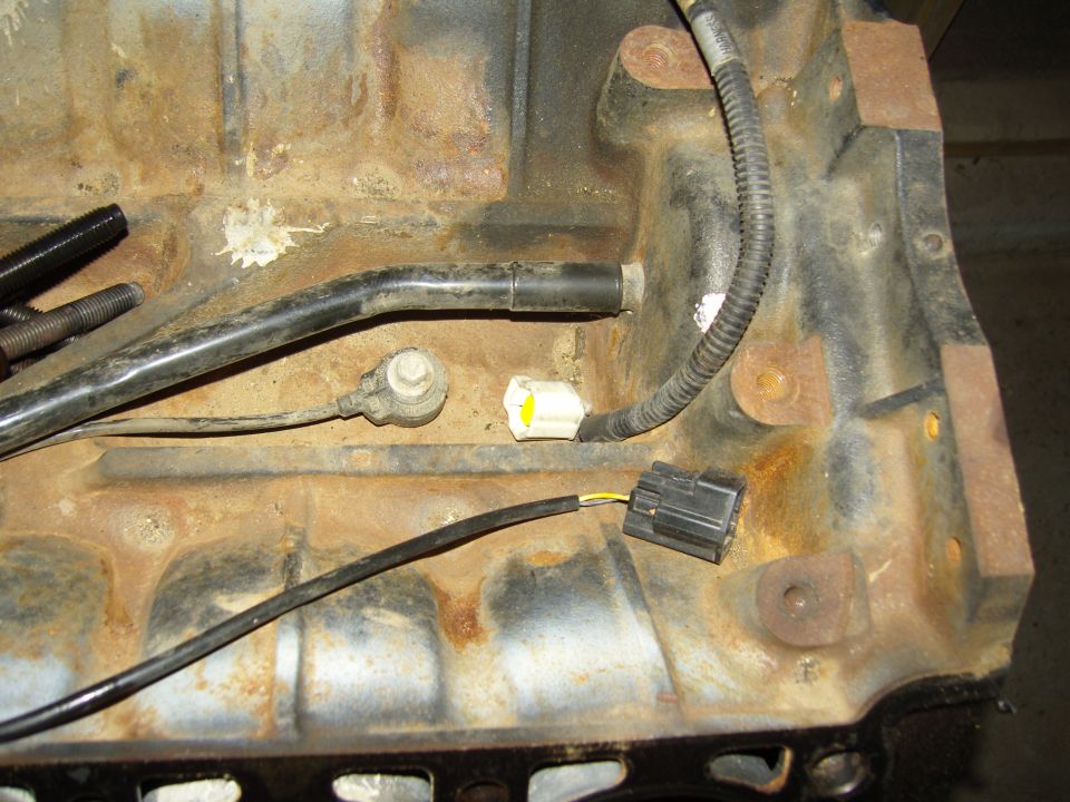 Underside of engine block with oil pickup tube and white wiring connectors