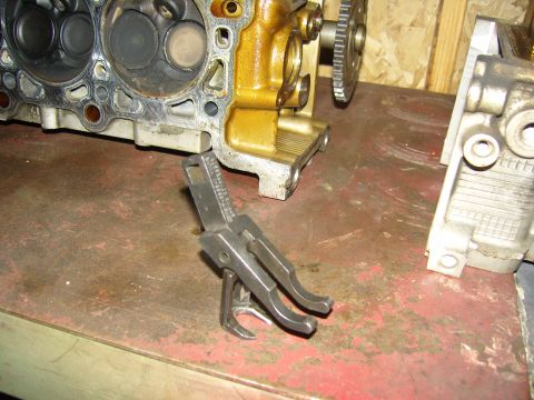 2007 Ford Mustang - Photograph of engine components including a cylinder head and a forked metal part on a workbench, not a technical document.