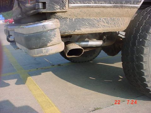 1989 Ford Bronco - The rear bumper and exhaust pipe of a 1989 Ford Bronco are visible, covered in dirt.