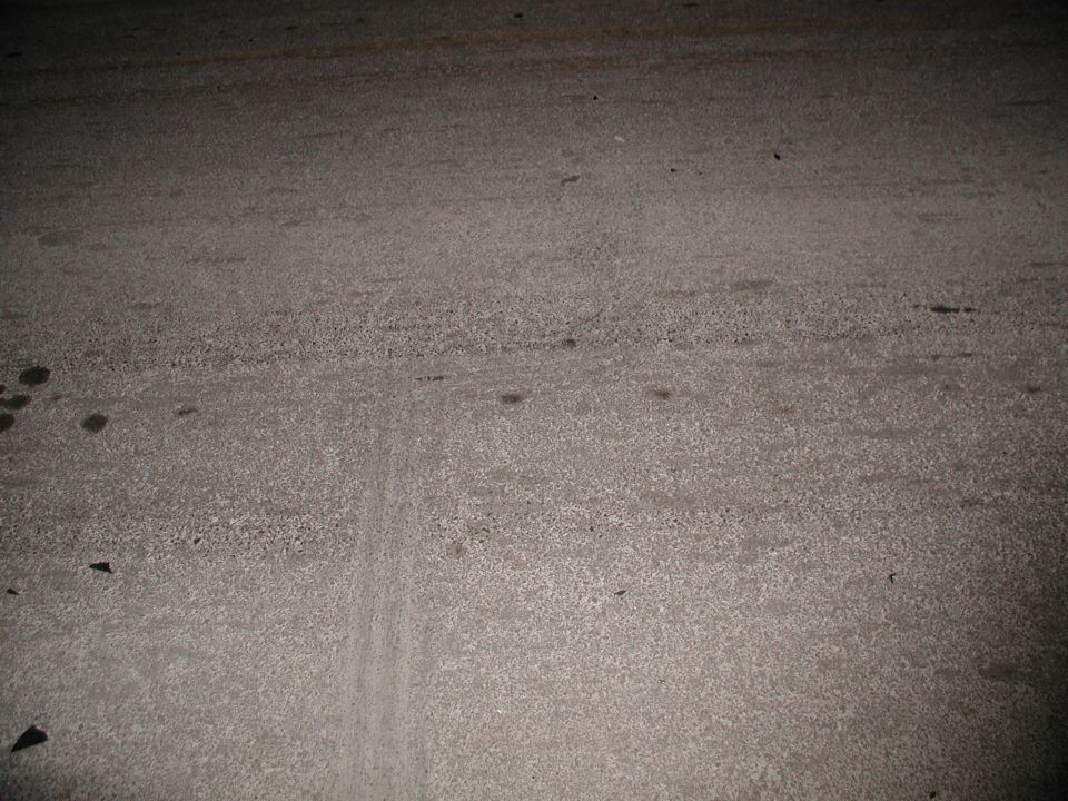 Coarse asphalt or concrete pavement at night with faint tire mark