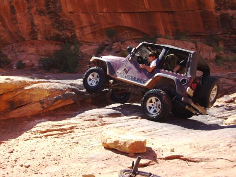 1995 Ford Bronco - A Jeep Wrangler navigates a rocky off-road trail under a canyon.