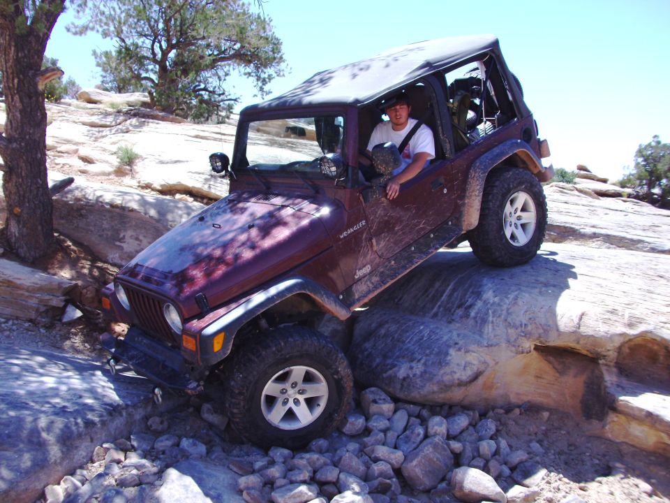 Maroon Jeep Wrangler TJ off-roading over rocks
