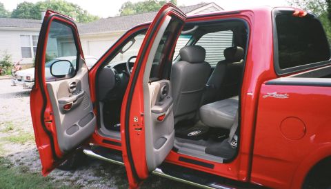 2007 Ford Mustang - Interior view of a red pickup truck with the doors open, showing gray seats and floor mats.