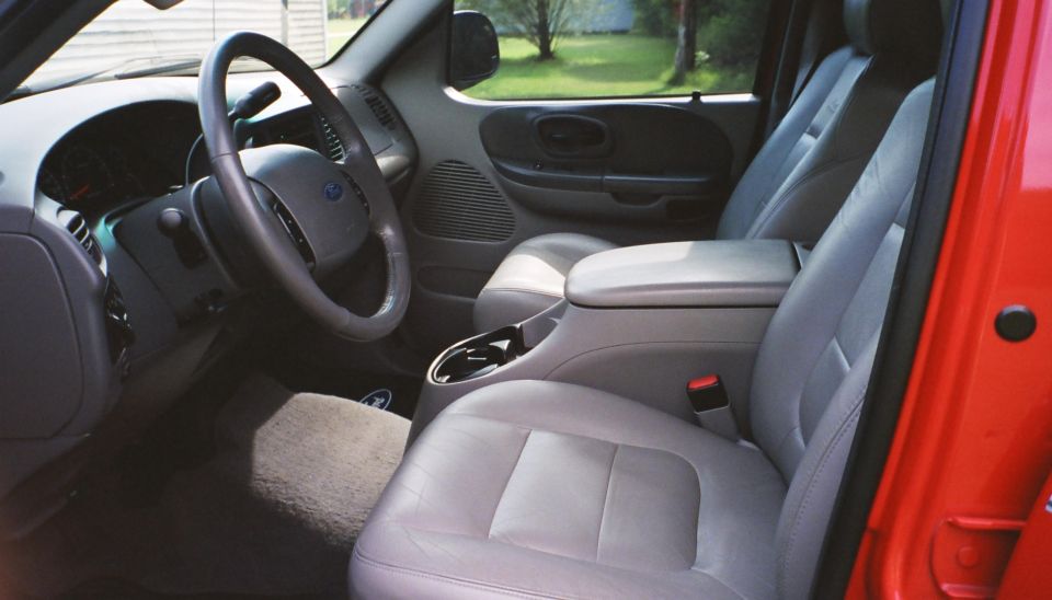 Interior view of a red pickup truck, showing gray leather seats, center console, and steering wheel