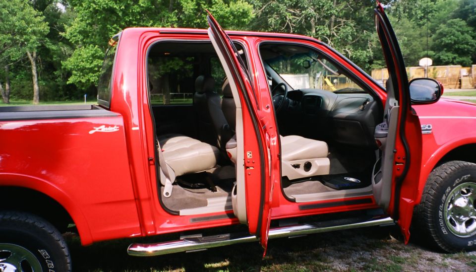 Red pickup truck with front doors open, showing tan interior and seats