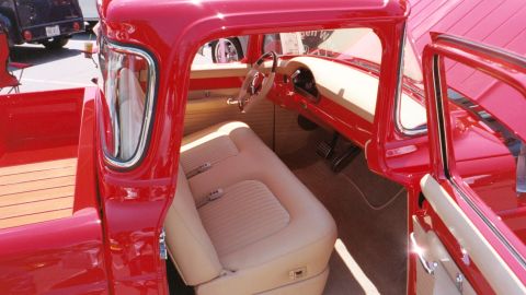 2007 Ford Mustang - The interior of a red pickup truck features tan upholstery and a wooden bed visible from the side.