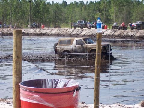 1992 Ford Bronco - A 1992 Ford Bronco navigates a muddy water obstacle at an off-road event.