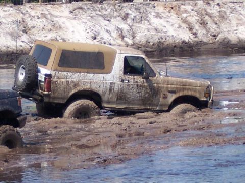 1992 Ford Bronco - This 1992 Ford Bronco is stuck deep in the mud and water, with another vehicle nearby.