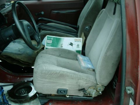 1987 Ford F-150 - Interior view of a 1987 Ford F-150, seats, steering wheel, and a box of motor oil on the passenger seat.