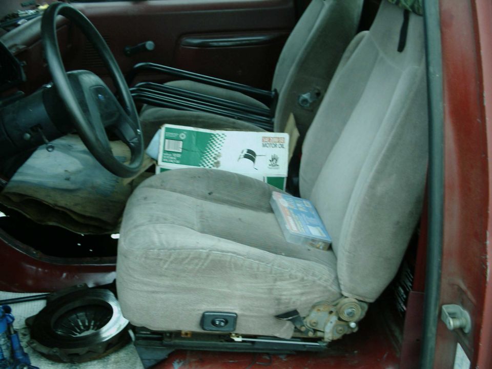 1987 Ford F-150 interior showing driver's seat, passenger seat, steering wheel, and a box of motor oil