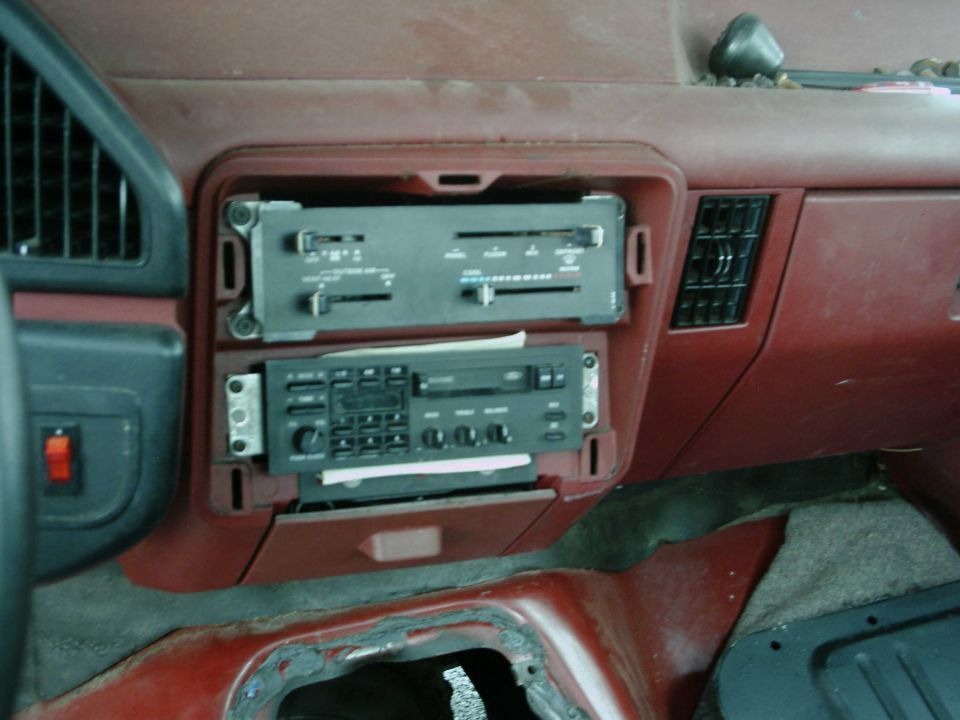 Car dashboard with two radios stacked, air vents, and a red switch