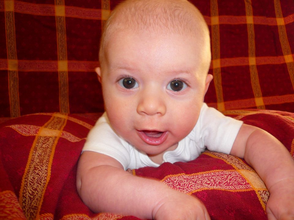 Baby lying on a red and yellow plaid blanket