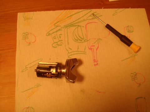 1992 Ford Bronco - Ignition lock cylinder and a small screwdriver are laid out on a paper towel with cartoon drawings.