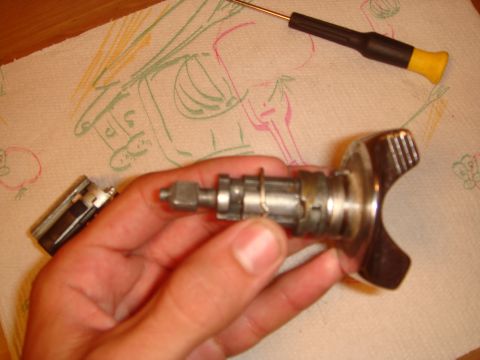1992 Ford Bronco - A car door lock cylinder and handle are disassembled on a paper towel with a screwdriver nearby.