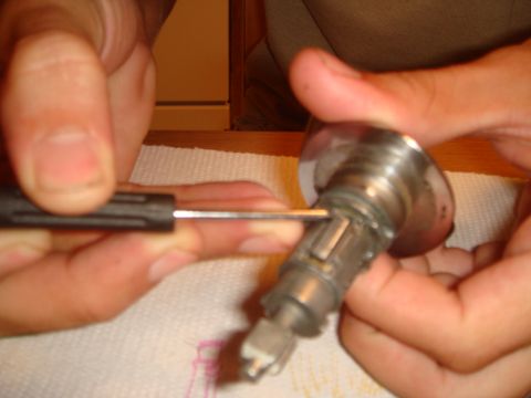1992 Ford Bronco - A close-up shows a screwdriver being used to manipulate a car's ignition lock cylinder.