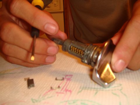 1992 Ford Bronco - A close-up shows a car's ignition lock cylinder being disassembled with a screwdriver.