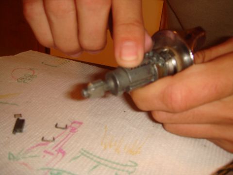 1992 Ford Bronco - Hands manipulate an ignition lock cylinder on a paper towel with colorful scribbles.