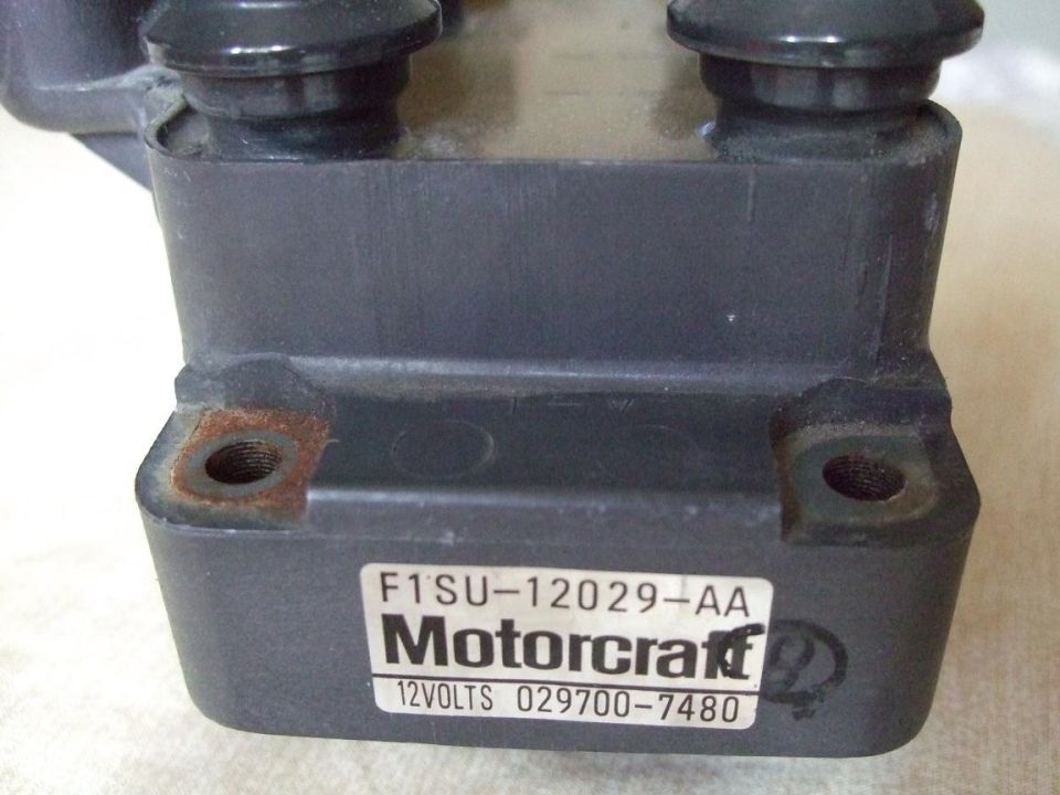Motorcraft ignition coil with part number F1SU-12029-AA and 12VOLTS 029700-7480, showing rust on mounting points
