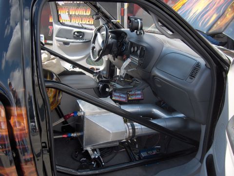 2007 Ford Mustang - The interior of a modified truck features a roll cage, aftermarket gauges, and a prominent intercooler system.