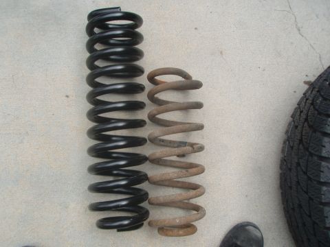 1987 Ford Bronco - Comparison of a new coil spring and an old, rusted one, with a tire in the background.