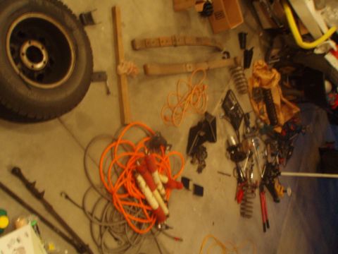 1987 Ford Bronco - A collection of tools and a spare tire are laid out on a garage floor.