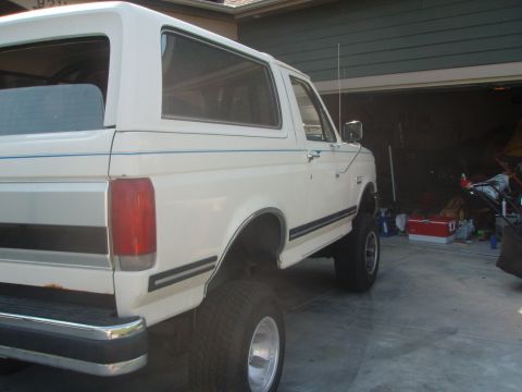 1987 Ford Bronco - White 1987 Ford Bronco with blue pinstripes, seen from the rear quarter angle in a garage.