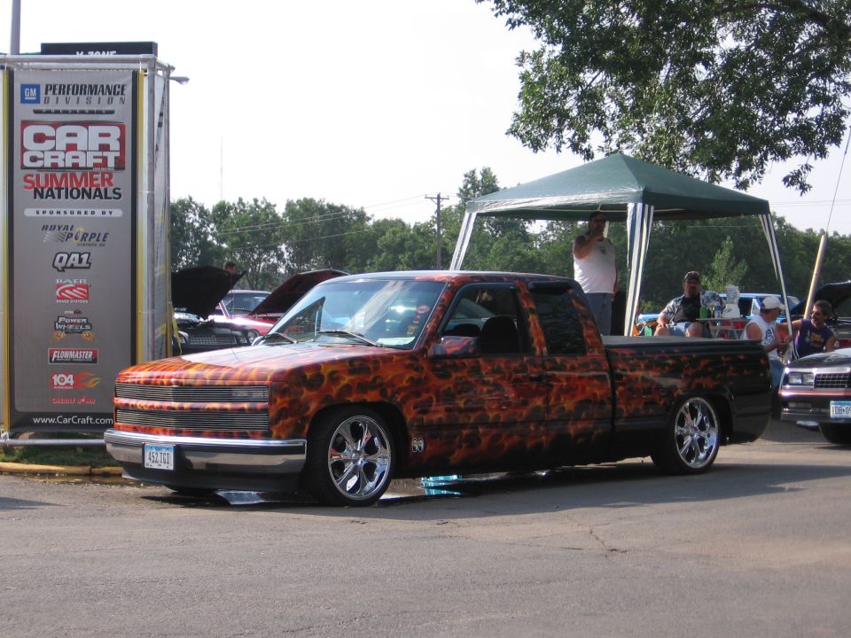 Truck with flame graphics, lowered, chrome wheels, parked outdoors