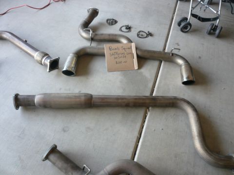 1996 Ford Probe - Several exhaust system components laid out on a concrete surface with a handwritten tag.